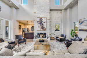 Cozy clubhouse lounge at Acclaim at South Congress with a tall stone fireplace, modern artwork, and comfortable seating.