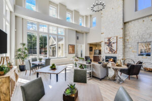 Another view of the clubhouse lounge, highlighting a stone fireplace, elegant furnishings, and a well-lit, inviting space.