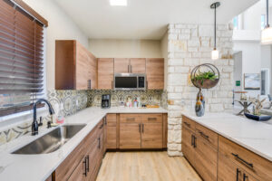 Interior kitchen area of the clubhouse at Acclaim at South Congress, featuring wooden cabinets, a stylish backsplash, and modern appliances.