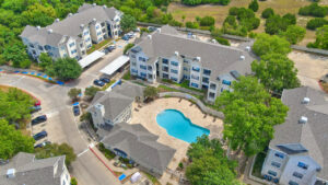 Aerial Exterior of Acclaim at South Congress, view of resort style pool, surrounding residential buildings, lush foliage.