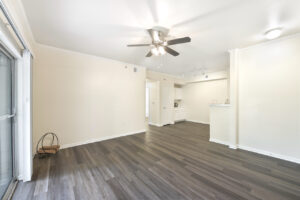 Spacious living area with a ceiling fan, wood-style flooring, and sliding glass doors leading to a private balcony.