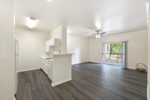 Open-concept kitchen and living space with dark wood-style flooring, white cabinetry, and natural light.