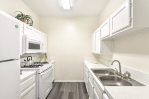 Galley-style kitchen with white appliances, overhead cabinets, and a modern, minimalist design.
