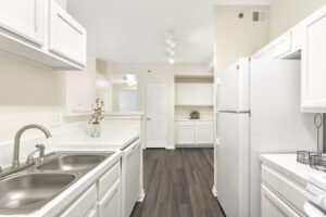Open kitchen with white cabinetry, solid surface countertops, stainless steel sink, and a pass-through counter.