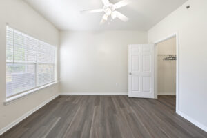 Bedroom with a ceiling fan, wood-style flooring, and a spacious walk-in closet.