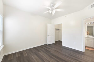 Bright bedroom with a ceiling fan, large window, and an attached walk-in closet.