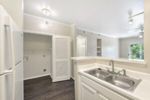 Kitchen area featuring a dual sink, white cabinetry, and an adjacent laundry closet.