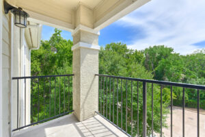 Private balcony with a black railing, overlooking lush greenery.