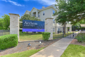 Gated entrance to the Acclaim at South Congress apartment complex with stone pillars and a sign.